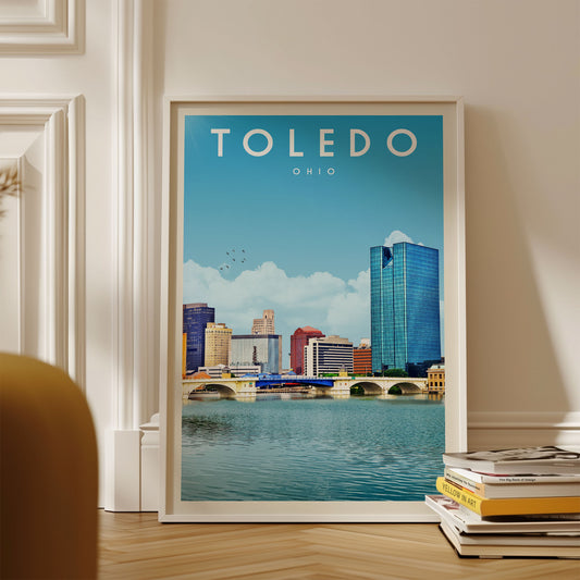 A framed poster of the city of Toledo, Ohio, featuring a skyline with tall buildings and a river in the foreground.