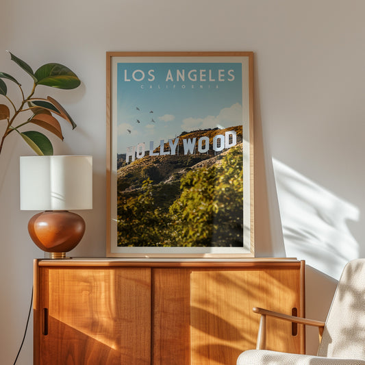a framed poster of Hollywood sign in Los Angeles, California, with a wooden cabinet and a lamp in the foreground.