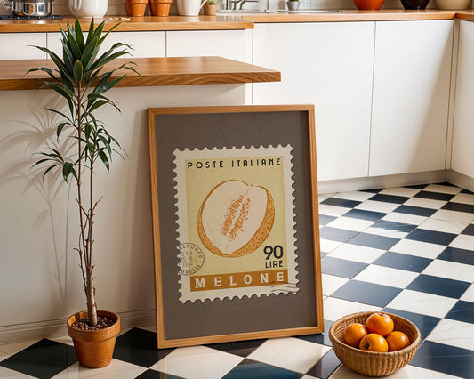 a framed Italian postage stamp with a melon, placed on a checkered floor next to a potted plant and a basket of oranges.