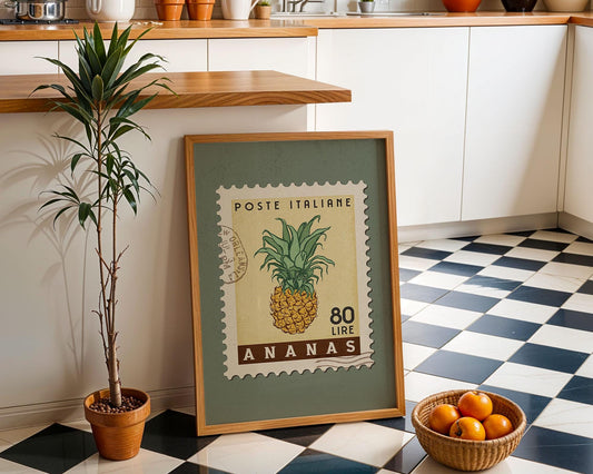 a framed stamp-like artwork depicting a pineapple, placed on a checkered floor next to a potted plant and a basket of oranges.