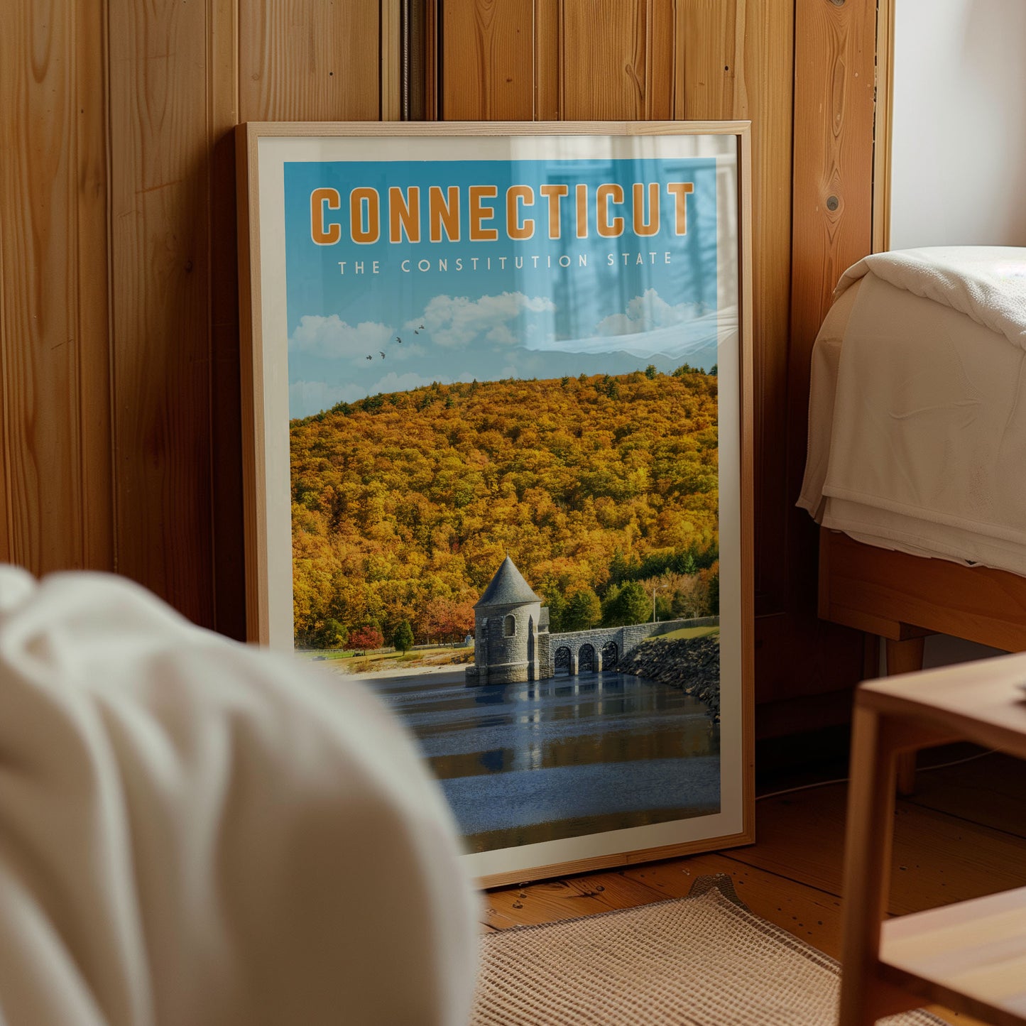 a framed poster of a scenic landscape with a small building, likely representing the Connecticut state.