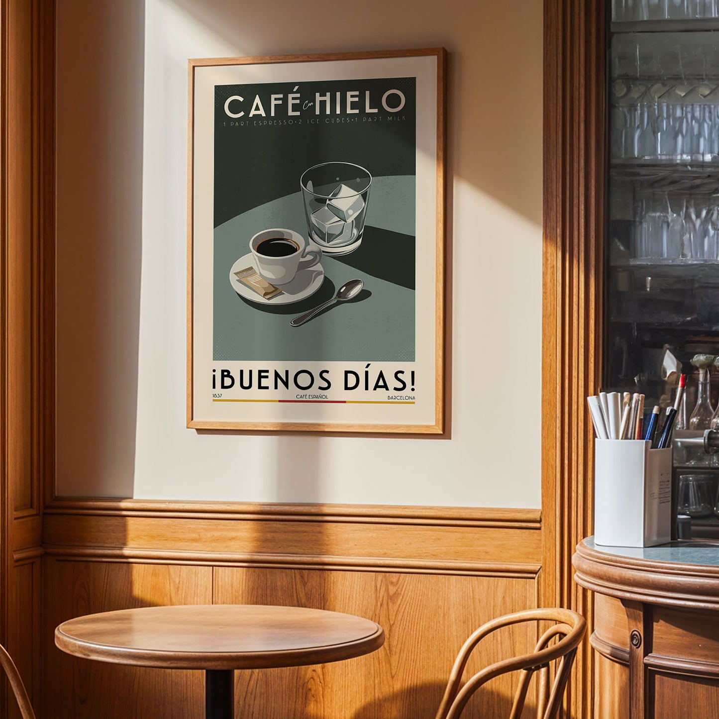 a framed poster of a coffee cup and saucer on a wall, with the text "CAFÉ HILO" and "IBUENOS DÍAS!" displayed prominently.
