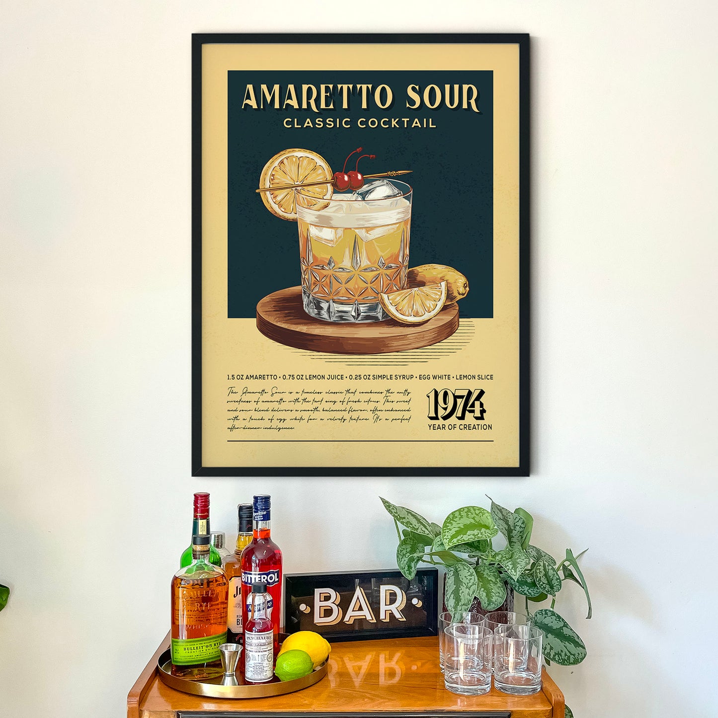 a framed poster of an Amaretto Sour cocktail hanging on a wall above a wooden bar counter with various liquor bottles and glasses.