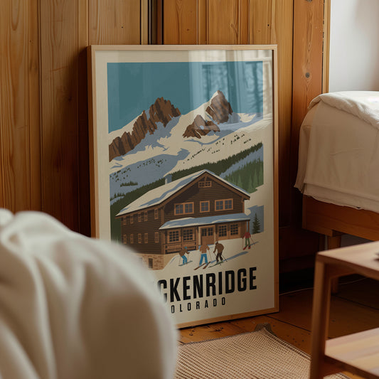 A framed poster of a mountain cabin with people skiing in the foreground, located in a room with wooden walls.