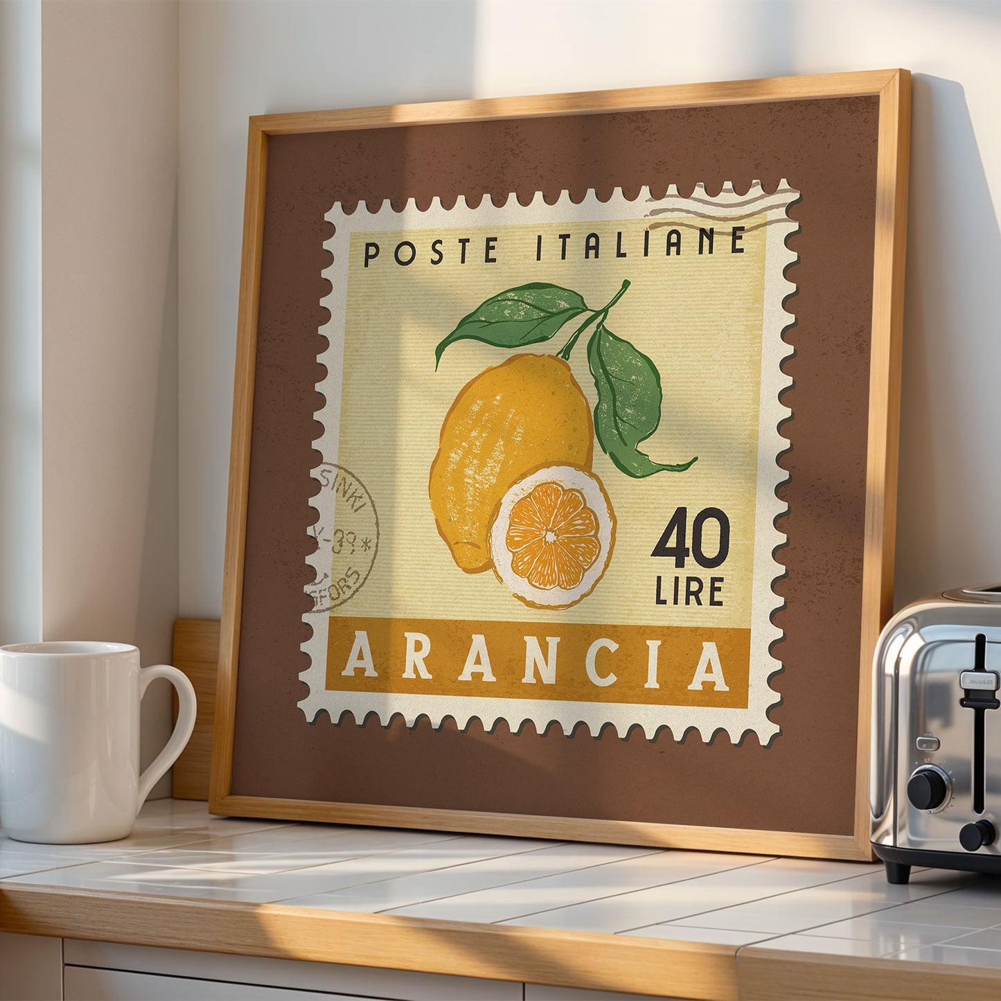 a framed stamp-like artwork depicting a lemon, with the text "POSTE ITALIANE" and "40 LIRE ARANCIA" printed on it. The artwork is displayed on a wooden shelf, with a white mug and a toaster visible in the background.