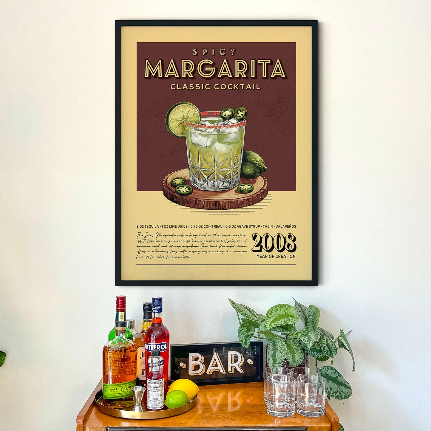a framed poster of a Margarita cocktail hanging on a wall above a wooden bar counter with various liquor bottles and glasses.