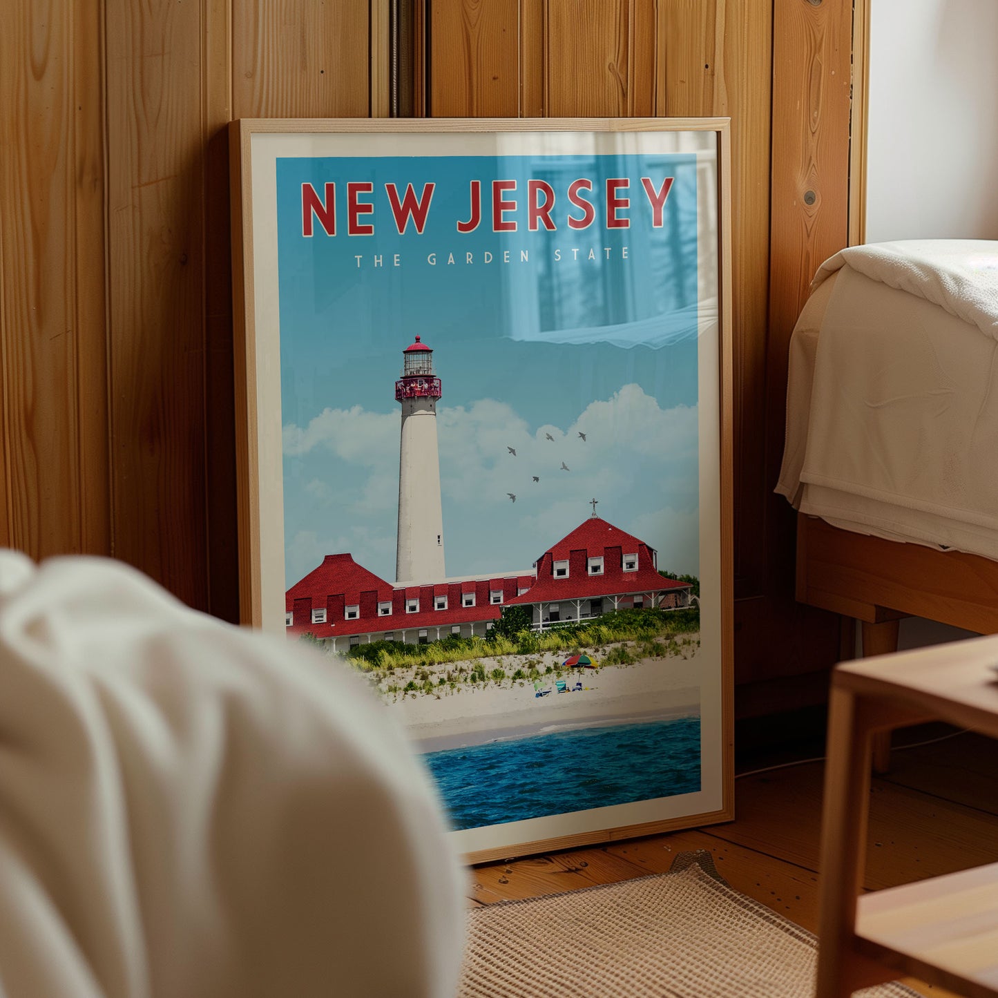 A framed poster of a lighthouse in New Jersey, with a beach and ocean in the background.