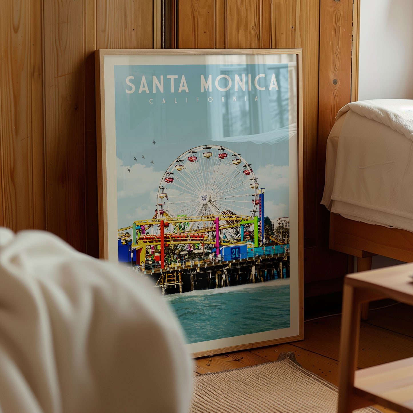 A framed poster of Santa Monica, California, featuring a ferris wheel and the ocean in the background.