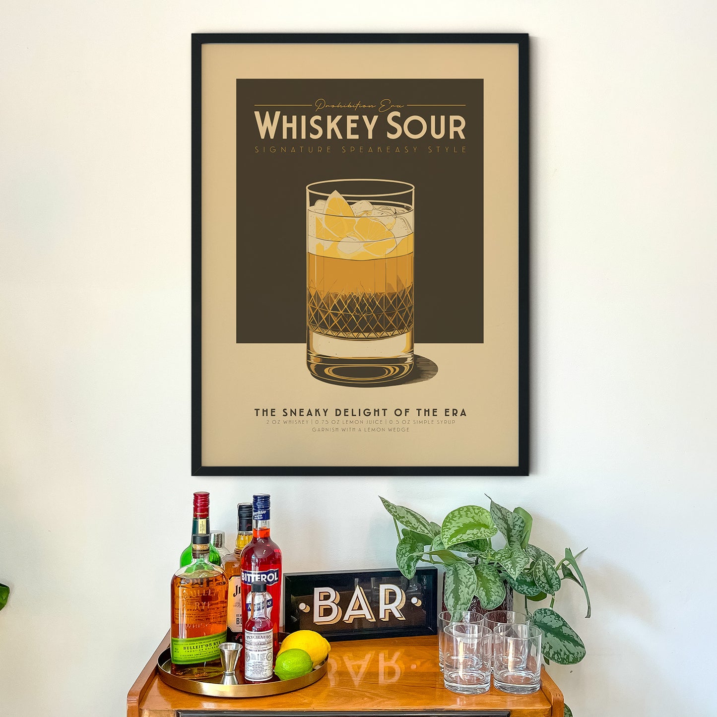 a framed poster of a whiskey sour on a wall, with a wooden bar counter below it displaying various liquor bottles and glasses.