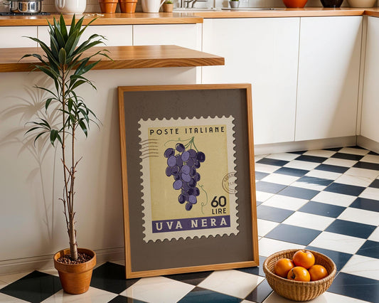 a framed stamp with a grape illustration, placed on a checkered floor next to a potted plant and a basket of oranges.
