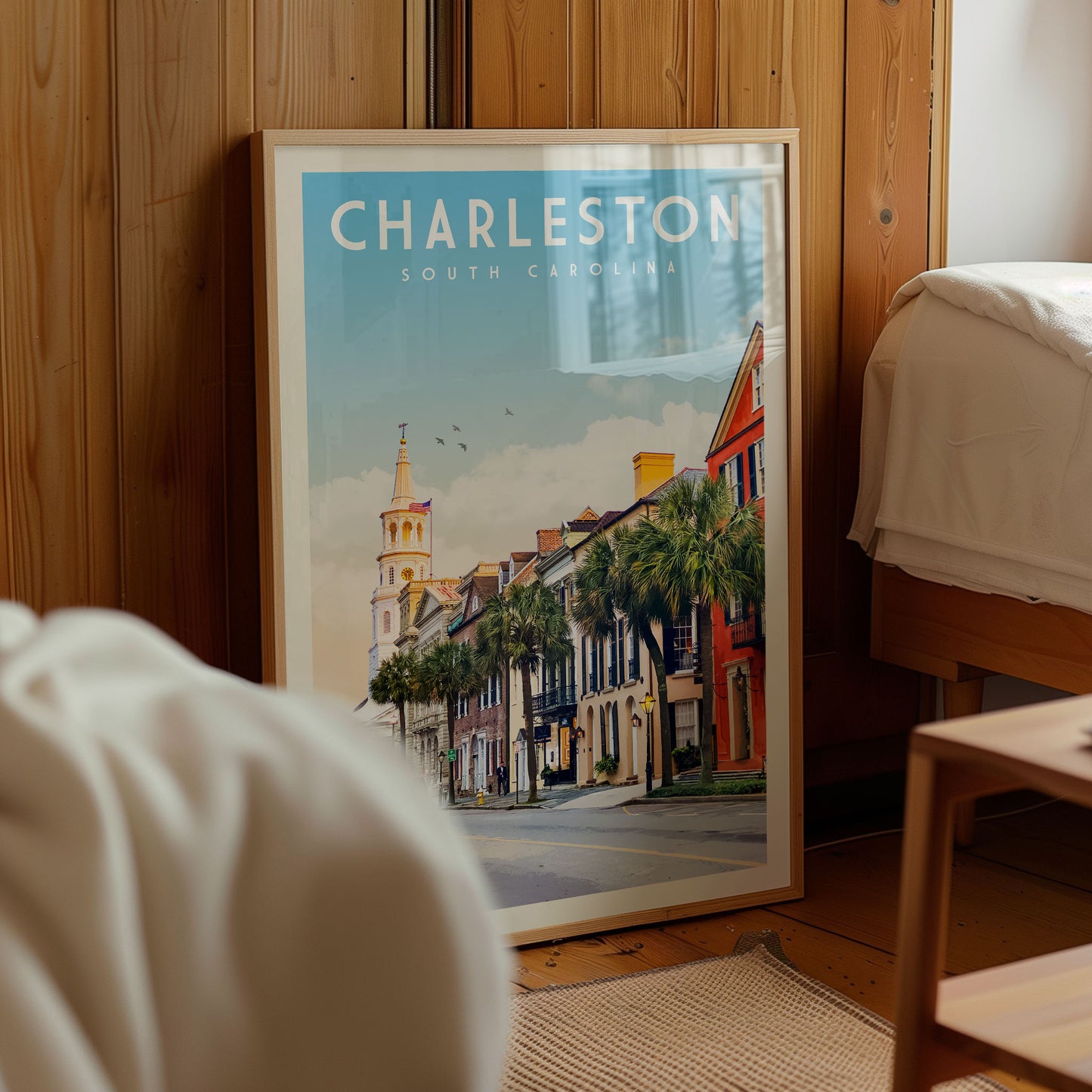 A framed poster of a street scene in Charleston, South Carolina, with a church steeple and palm trees in the background.