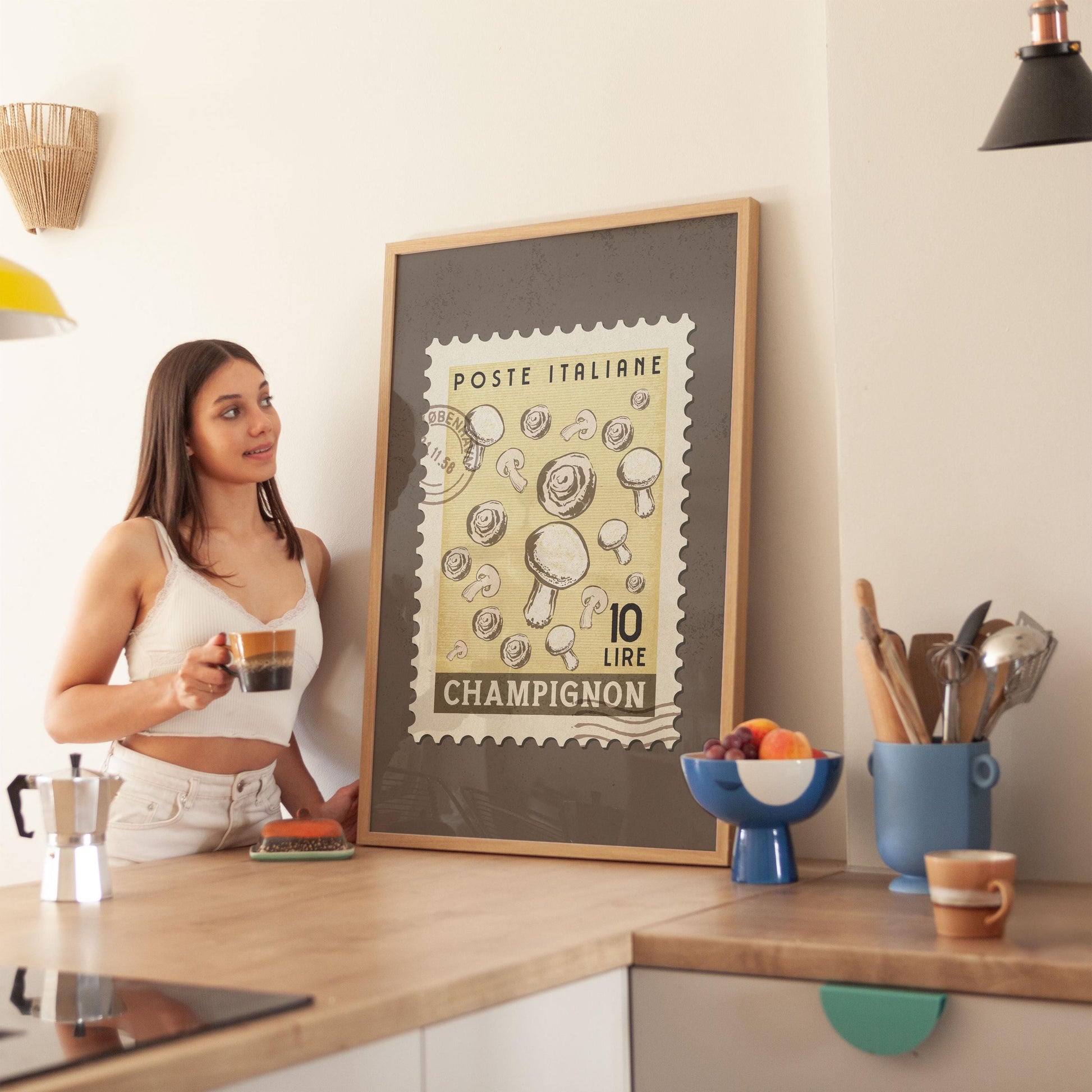 a woman standing in a kitchen next to a framed poster
