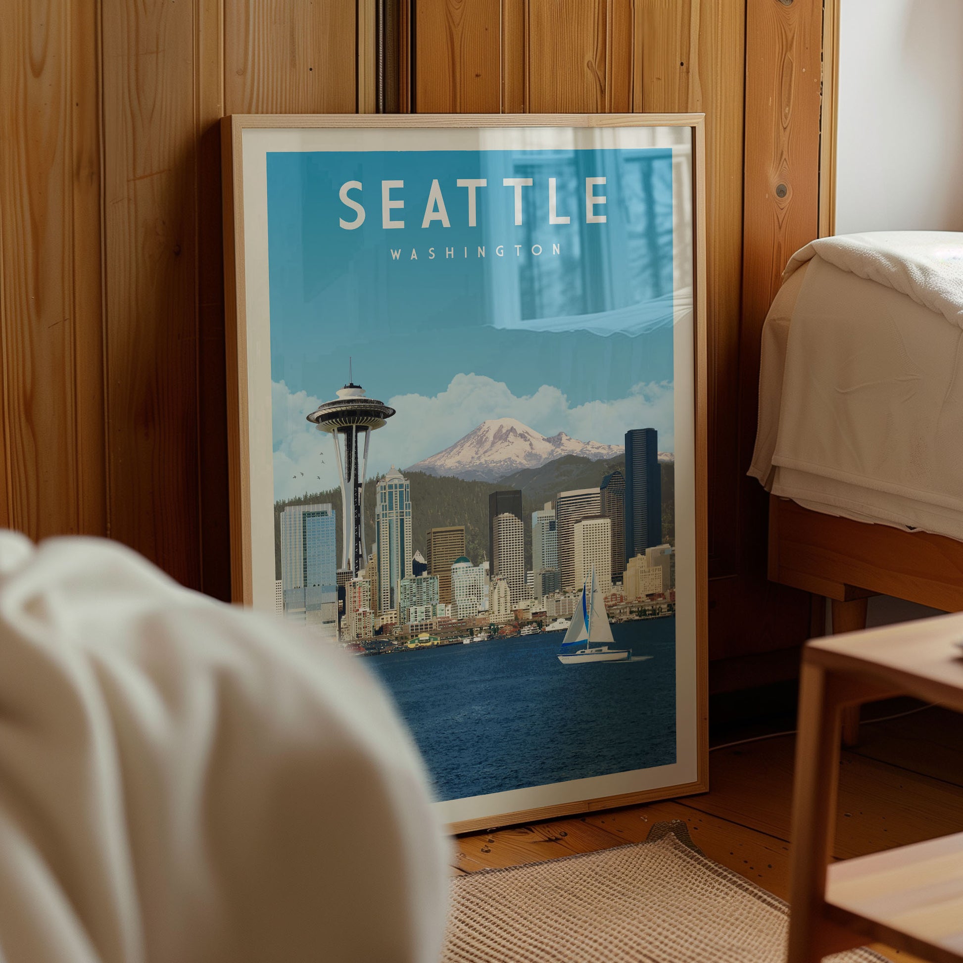 A framed poster of the Seattle skyline, featuring the Space Needle and the city's iconic skyline, is displayed in a room with a wooden wall.