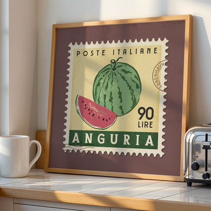 a framed stamp-like artwork depicting a watermelon, with the text "POSTE ITALIANE 90 LIRE ANGURIA" printed on it. The artwork is displayed on a shelf next to a toaster, creating a kitchen-themed setting.