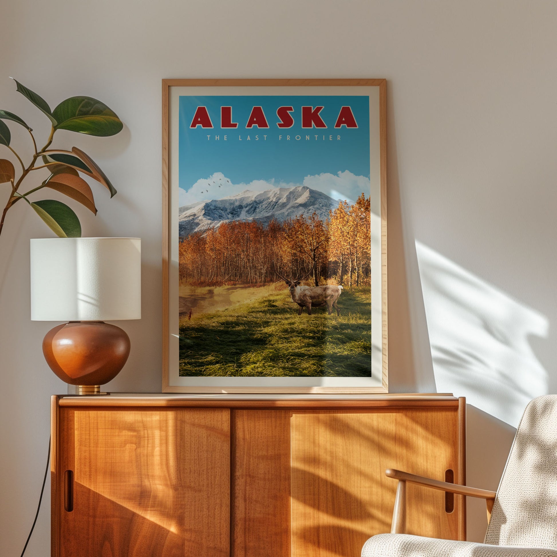 a framed poster of a scenic landscape with mountains and trees, hanging on a wall next to a wooden cabinet and a lamp.