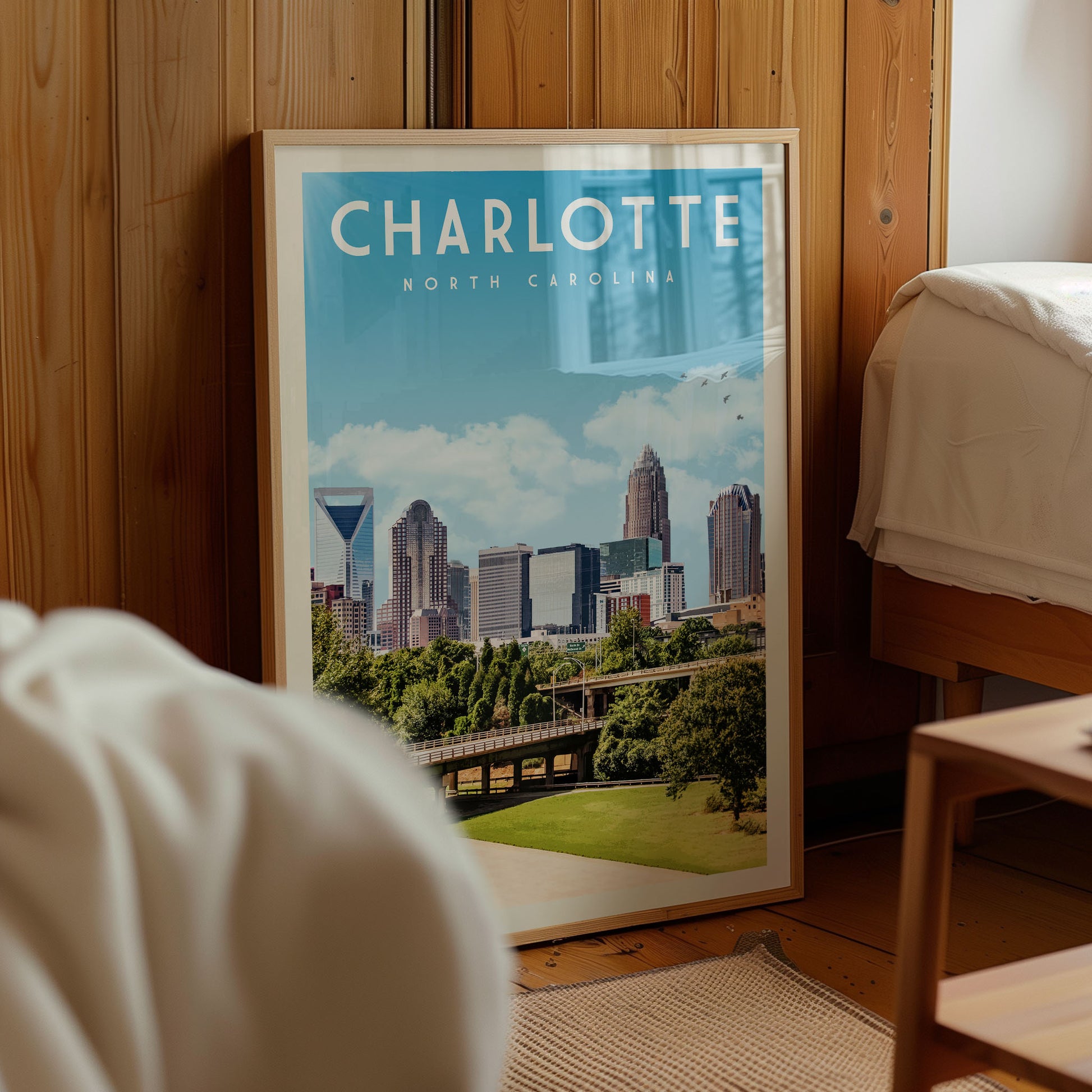 A framed poster of the skyline of Charlotte, North Carolina, with a cityscape and a bridge visible.