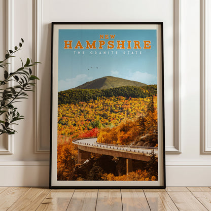The image is a framed poster of a scenic autumn landscape in New Hampshire, featuring a winding road, a mountain, and colorful foliage.