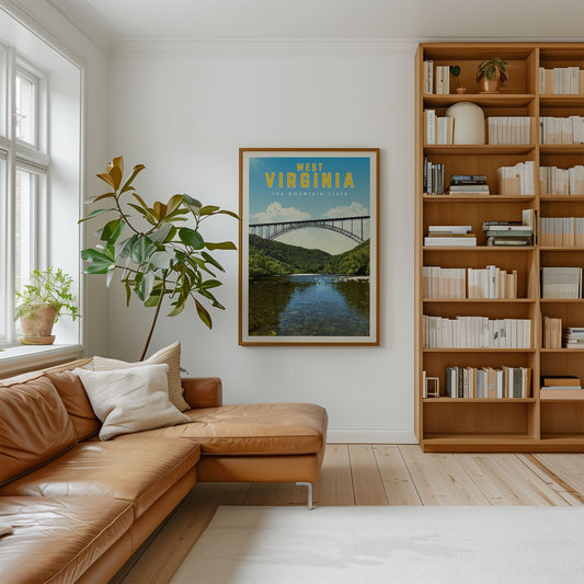 a cozy living room with a large window, a comfortable leather couch, a bookshelf filled with books, and a framed poster of a bridge in Virginia.