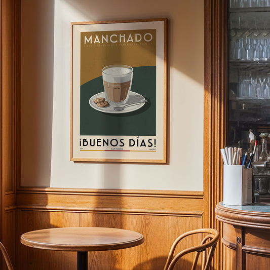 a framed poster of a cup of coffee on a table, with the text "Manchado" and "ibunos dias!" written on it.