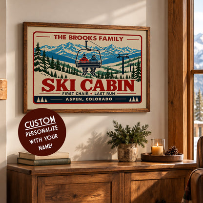 a framed poster of a ski cabin with a ski lift, displayed on a wall above a wooden cabinet.