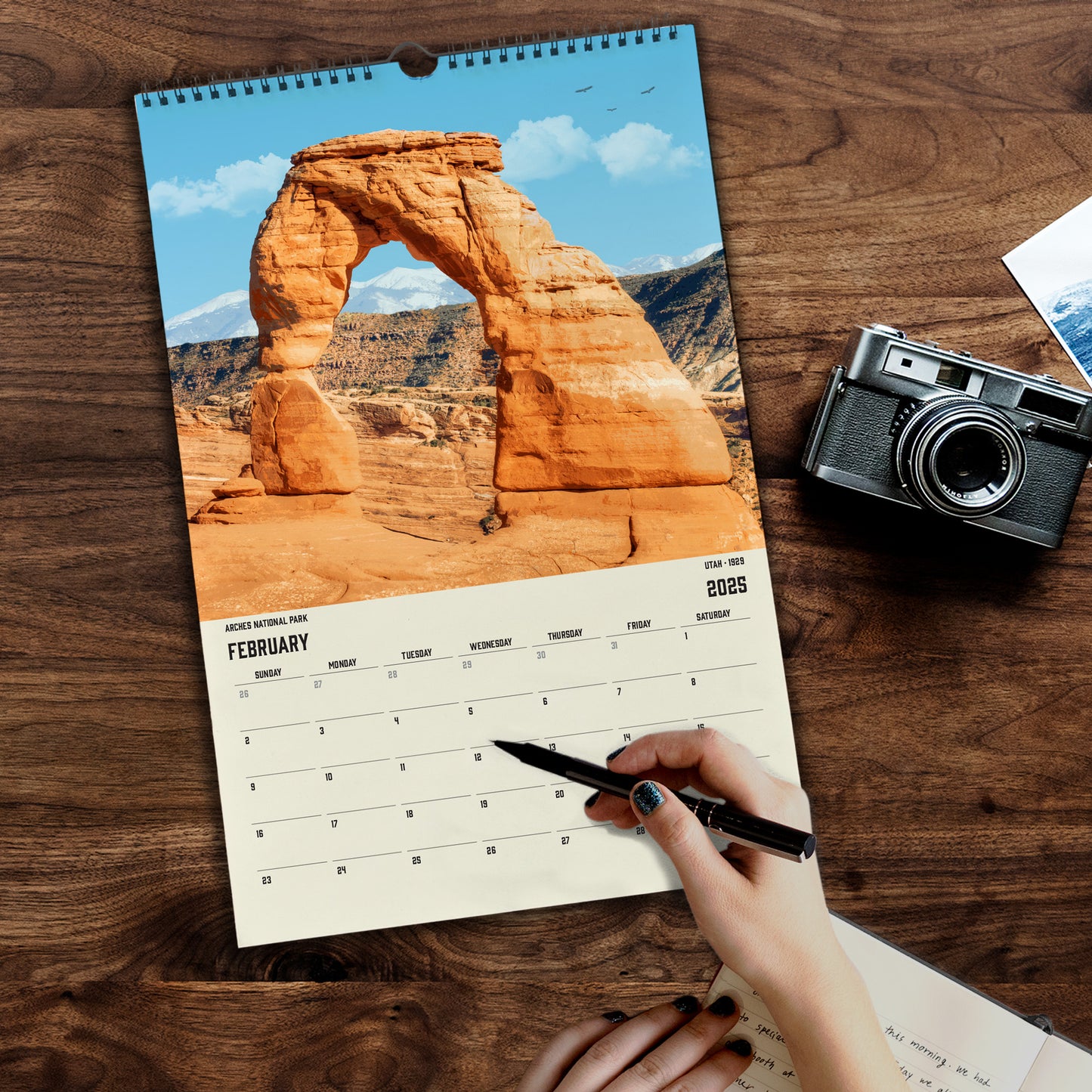 a calendar with a hand holding a pen and a camera