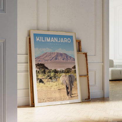 A large framed poster of a mountain landscape with an elephant in the foreground, displayed on a wall in a room.