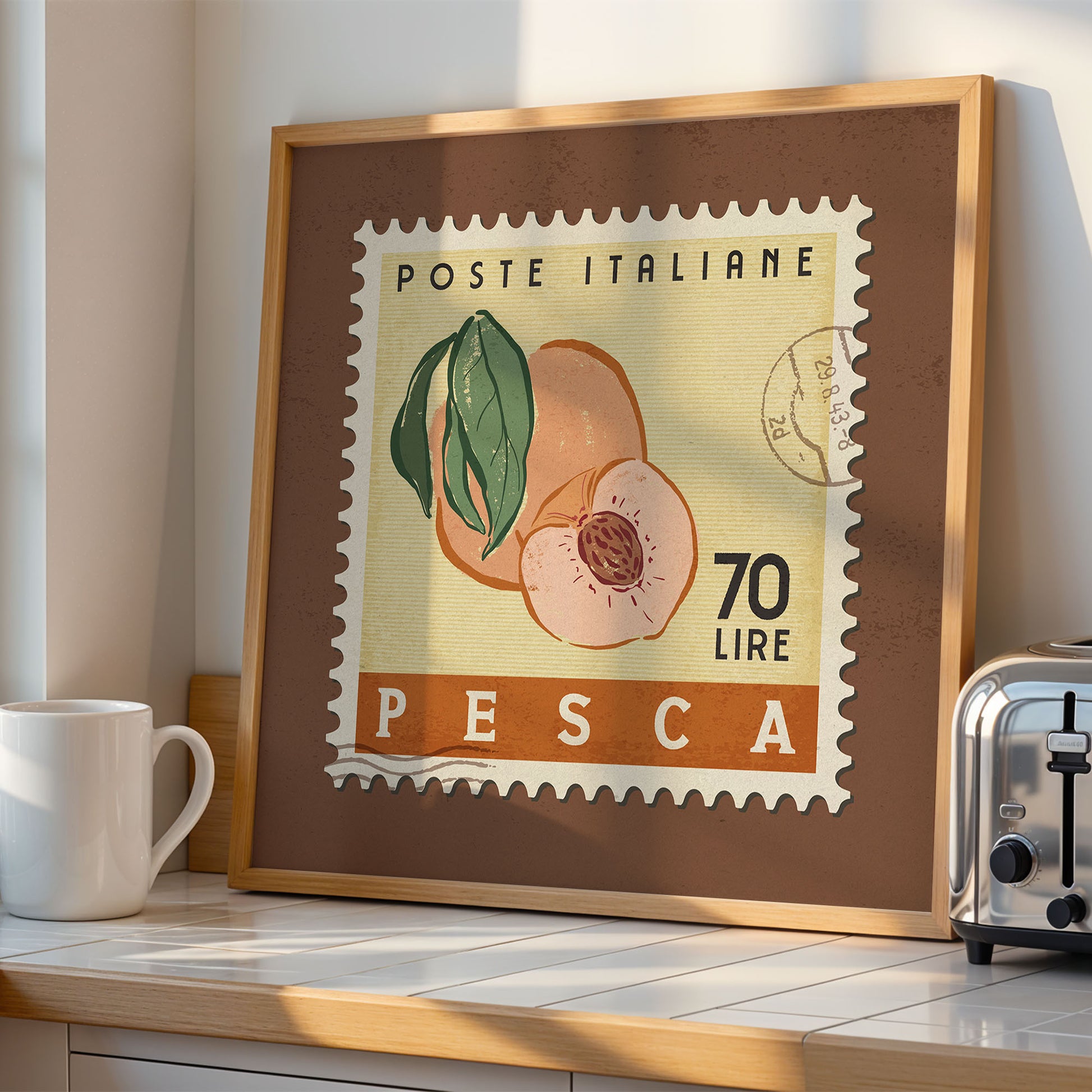 a framed stamp-like artwork depicting a peach, with the text "POSTE ITALIANE 70 LIRE PESCA" printed on it. The artwork is displayed on a wooden shelf, with a white mug and a toaster visible in the background.