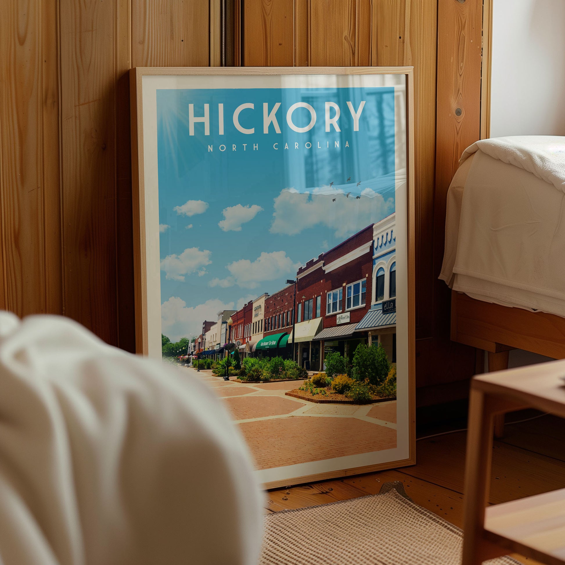 A framed poster of a street scene in Hickory, North Carolina, displayed in a room with wooden walls.