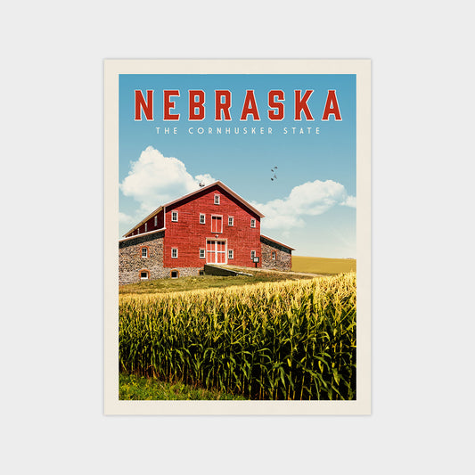 a red barn in a field of tall green corn, with a clear blue sky and fluffy white clouds in the background.