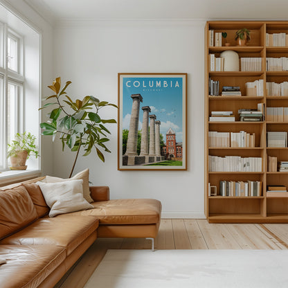 a cozy living room with a large bookshelf filled with books, a comfortable leather couch, and a framed poster of the historic city of Columbia, Missouri, featuring a row of columns.