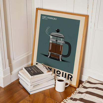 a framed poster of a French press coffee maker, a stack of books, and a cup of coffee on a wooden floor.