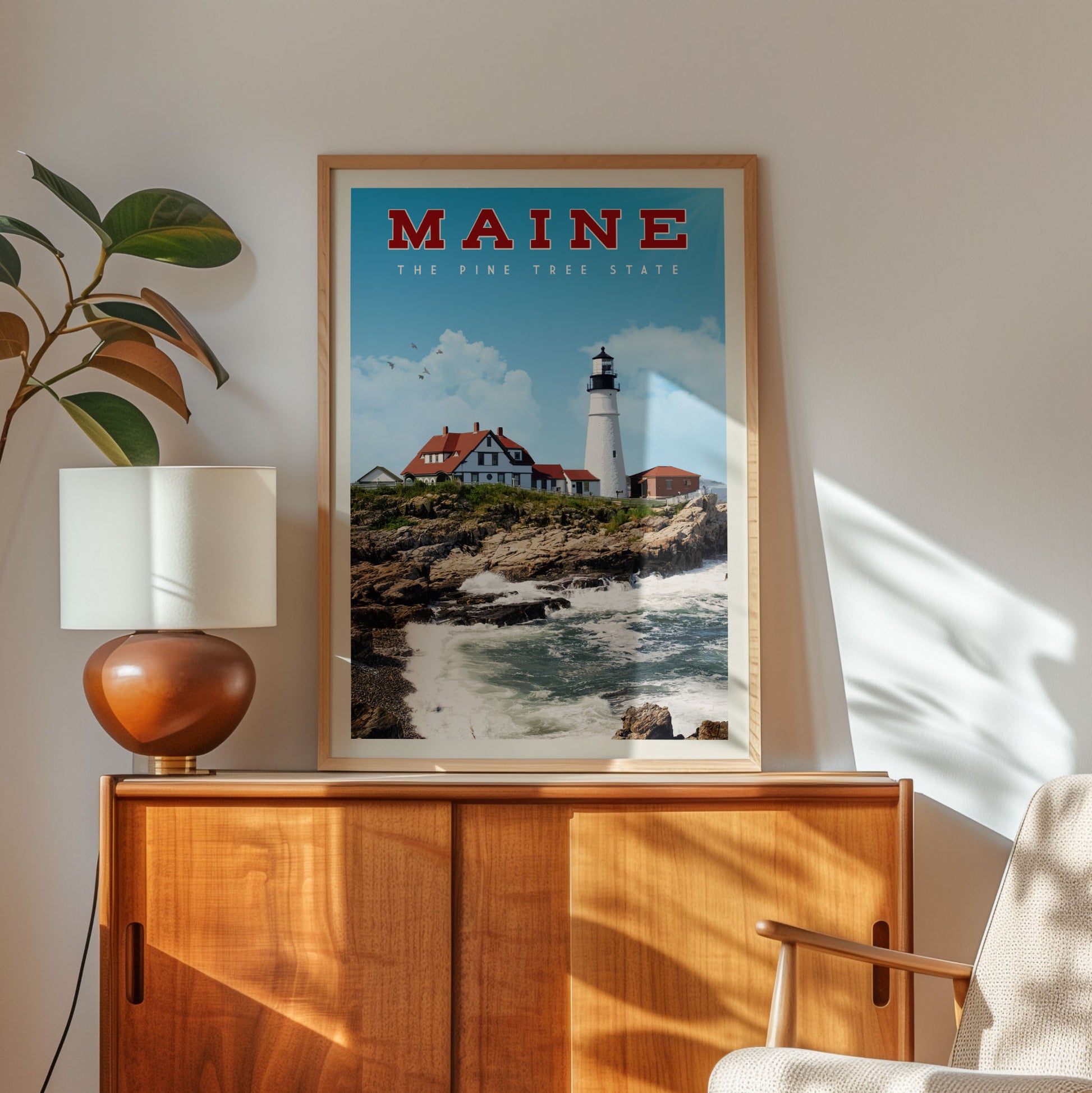 a framed poster of a lighthouse on a wall, with a wooden cabinet below it and a plant to the left.
