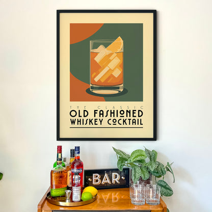 a framed poster of a whiskey cocktail on a wall above a wooden bar cart with various liquor bottles and glasses.