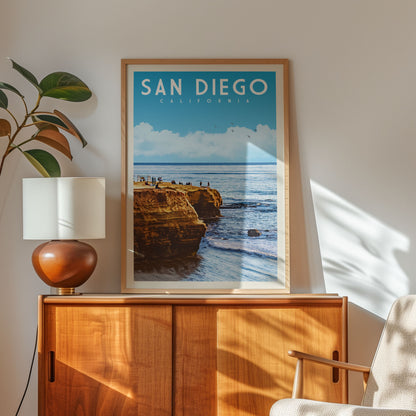 a framed poster of a scenic coastal landscape with cliffs and the ocean, hanging on a wall above a wooden cabinet.