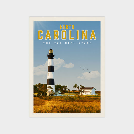 A lighthouse stands tall against a clear blue sky, with a small white house nestled in the distance.