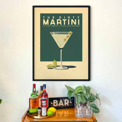 a framed poster of a martini glass with a cocktail, accompanied by a wooden bar display with various liquor bottles and glasses.