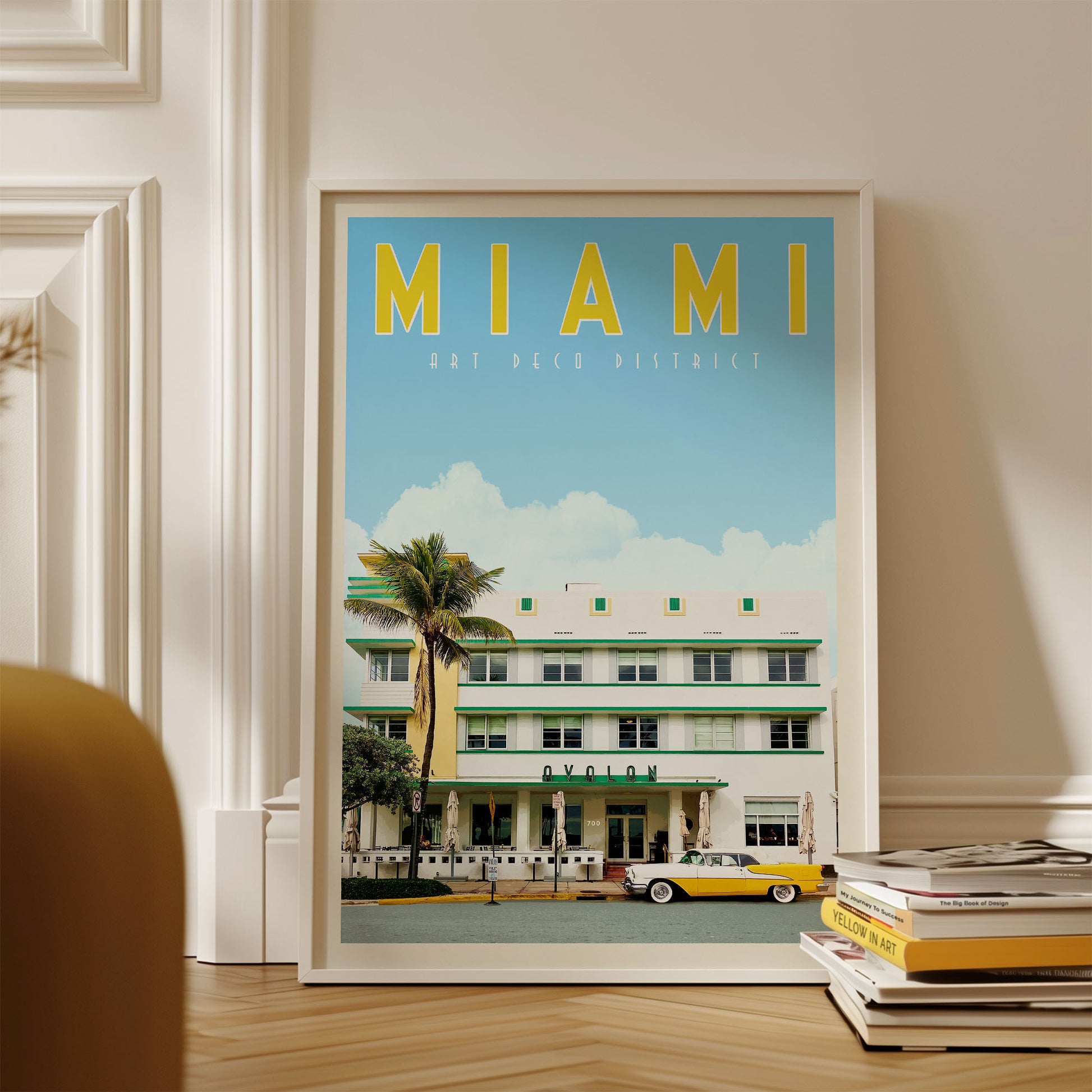 A framed poster of the Art Deco District in Miami, Florida, featuring a yellow and green building with palm trees and a yellow taxi in the foreground.
