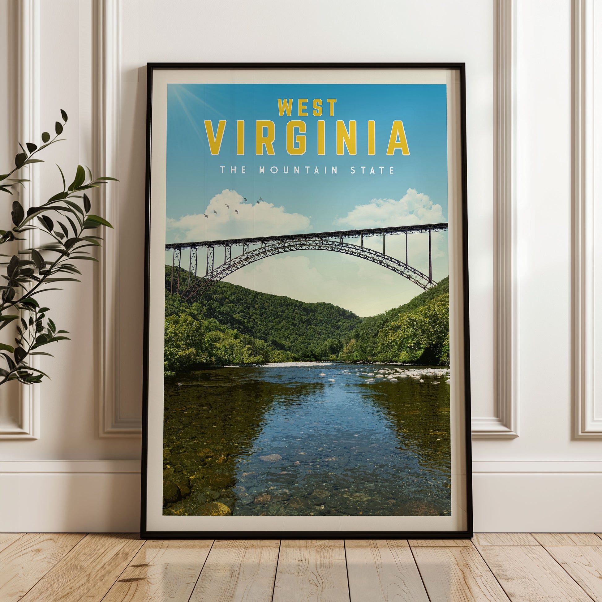 A framed poster of the West Virginia mountain state, featuring a bridge over a river surrounded by lush green hills.