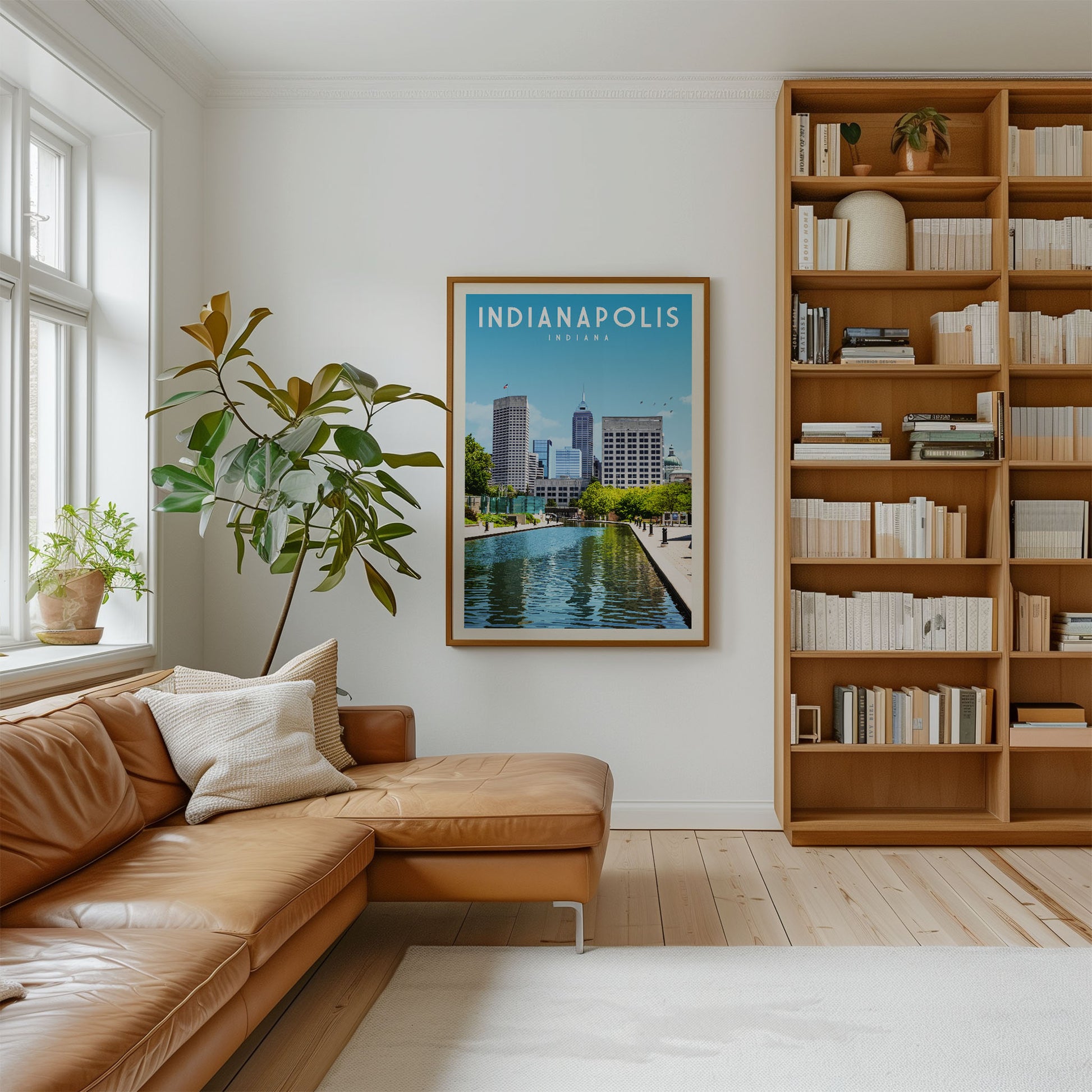 a living room with a large window, a brown leather sofa, a bookshelf filled with books, and a framed poster of Indianapolis, Indiana, hanging on the wall.