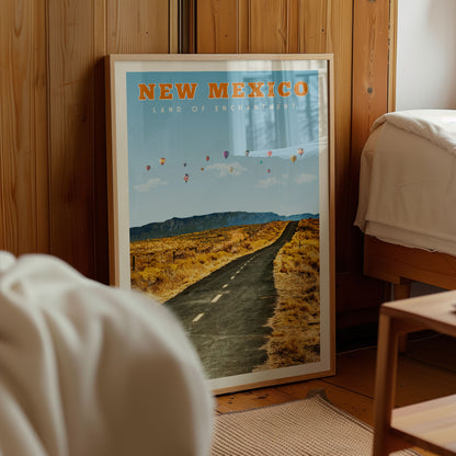 a framed poster of a desert road with hot air balloons in the sky, located in a room with wooden walls.