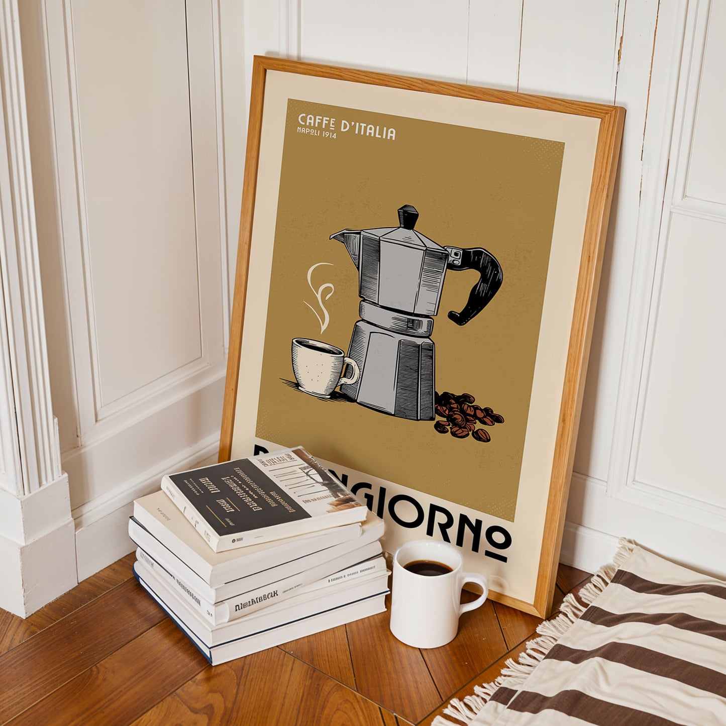 A framed poster of a coffee maker is leaning against a wall, with a stack of books and a cup of coffee nearby.
