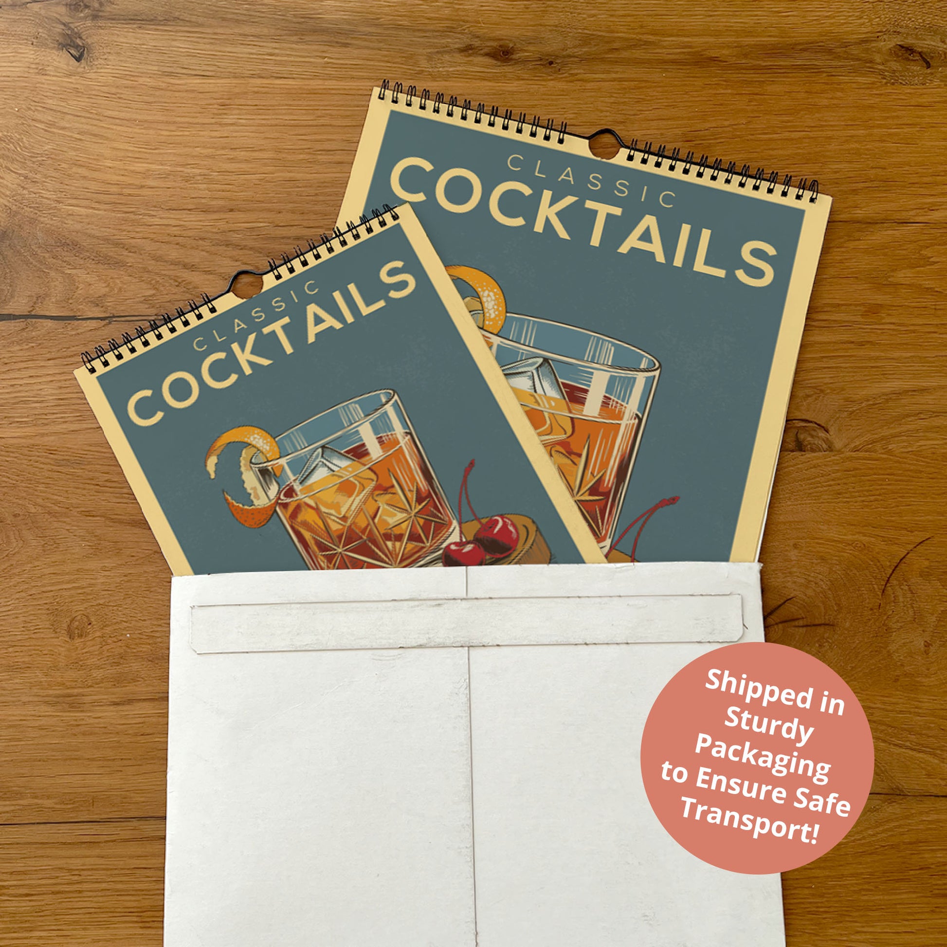 A spiral-bound calendar for "Classic Cocktails" is placed inside a white envelope on a wooden surface.