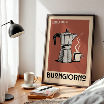 a framed poster of a coffee maker with a cup of coffee next to it, placed on a wooden floor next to a lamp and some books.