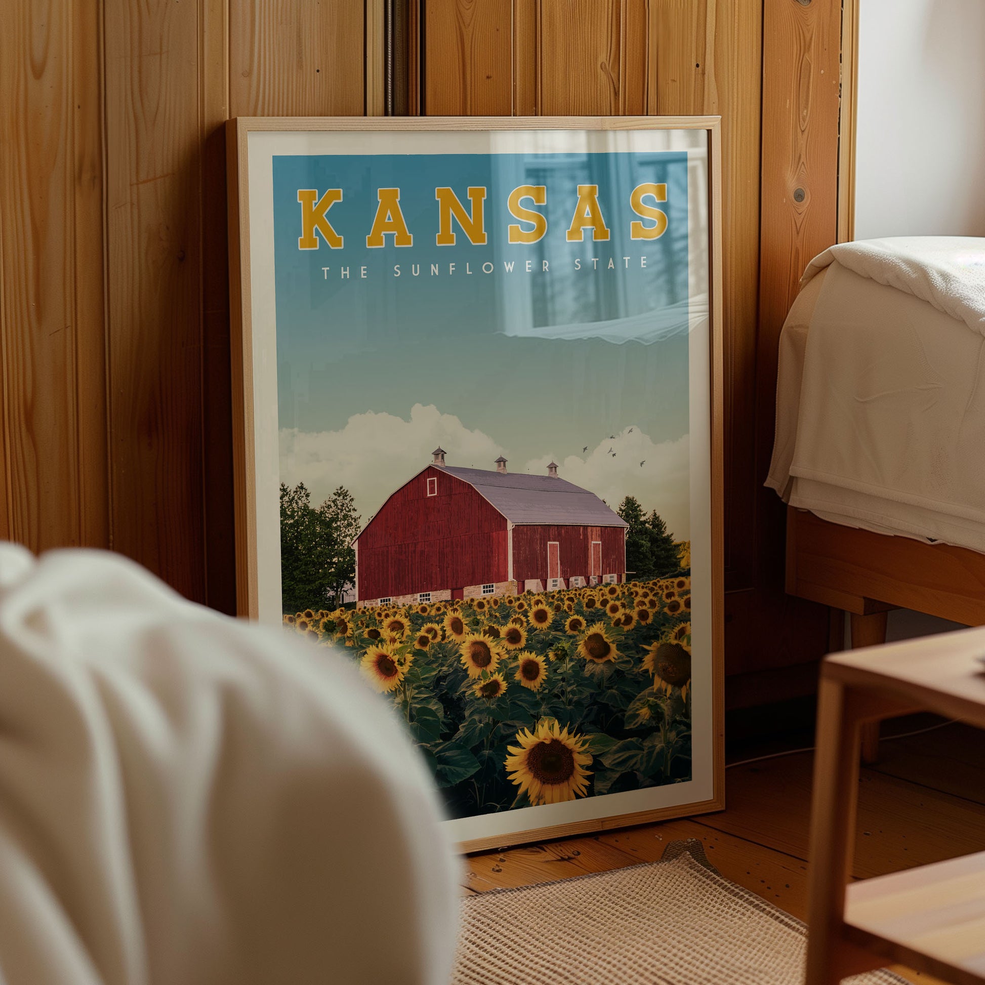 A framed poster of a red barn surrounded by a field of sunflowers, with the text "KANSAS THE SUNFLOWER STATE" prominently displayed.