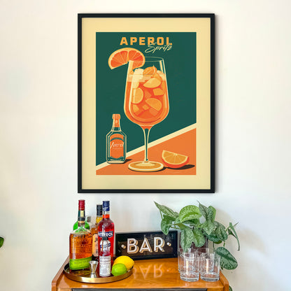 a framed poster of a cocktail glass with a drink and garnish, along with a bar display with various bottles of alcohol and a sign that says 'BAR'.
