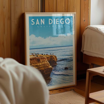 A framed poster of a scenic coastal landscape with cliffs and people enjoying the view, displayed in a room with wooden walls.