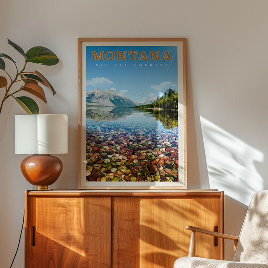a framed poster of a scenic landscape with mountains, water, and a lake, hanging on a wall above a wooden cabinet.