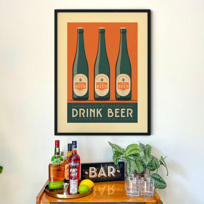 a framed poster with three bottles of beer and the text "DRINK BEER" above them, hanging on a wall above a bar cart.