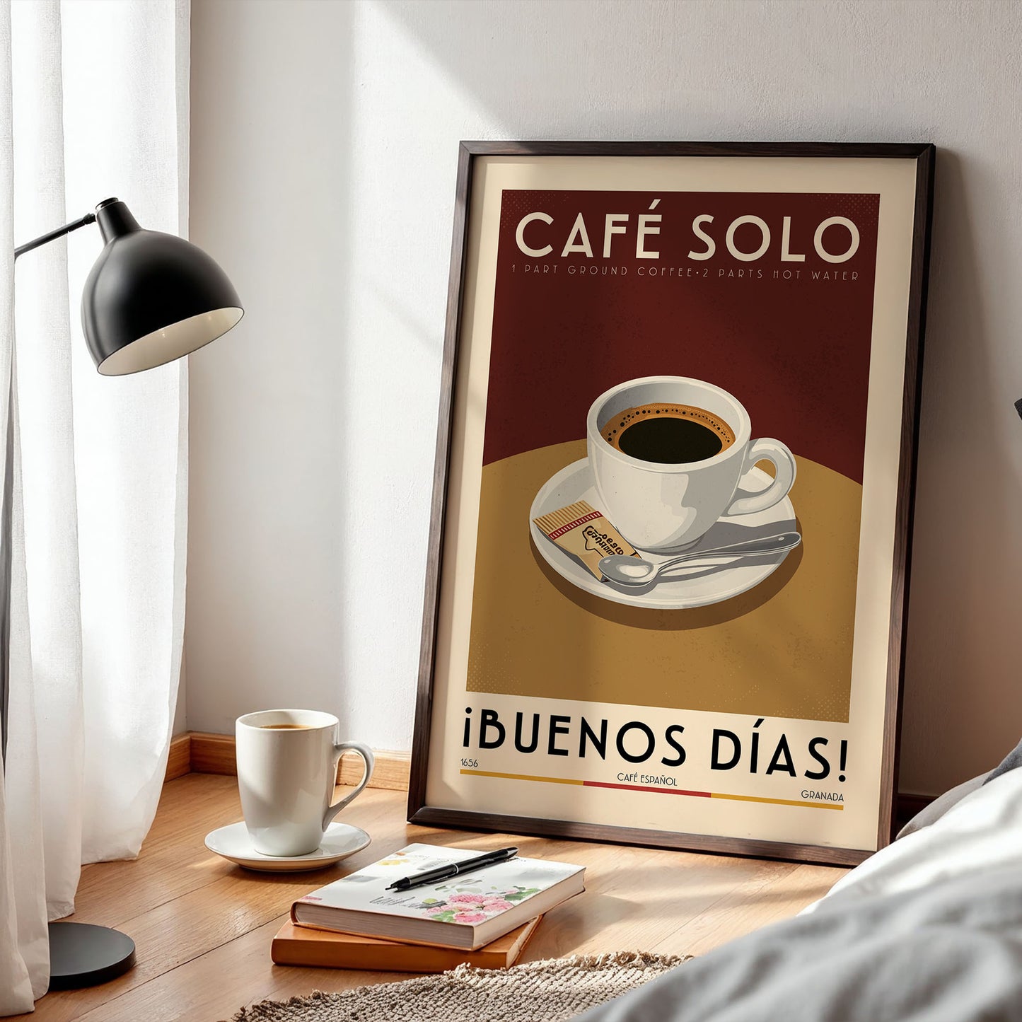 a framed poster of a cup of coffee on a table, with a lamp and a book nearby.