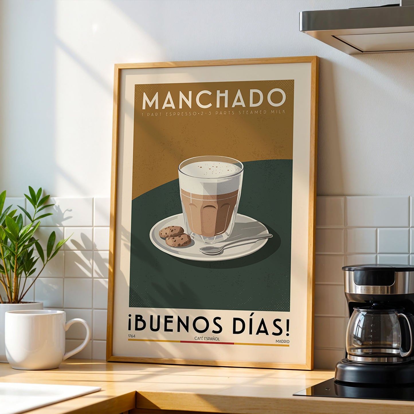 a framed poster of a cup of coffee with a cookie on a plate, placed on a kitchen counter next to a coffee maker.